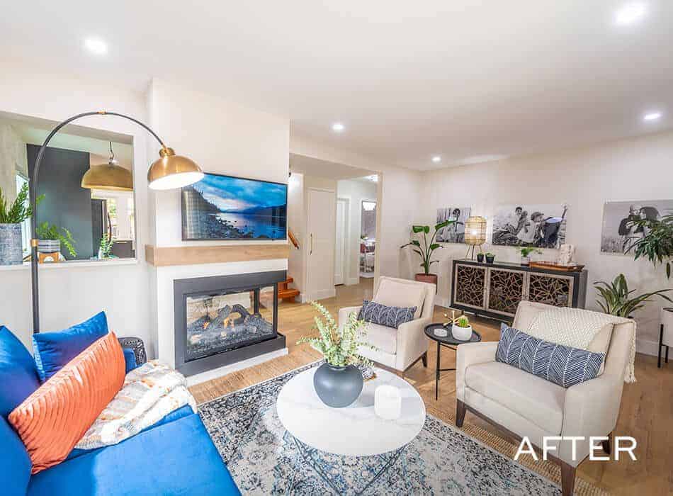 Bright living room with a fireplace, blue sofa, white armchairs, and decorative accents