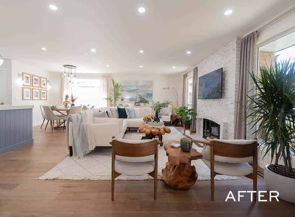 Open-concept living room with a white sofa, wooden furniture, a brick fireplace, and large windows