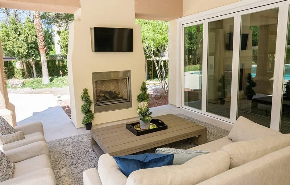 Covered outdoor seating area with a fireplace, mounted TV, and a coffee table
