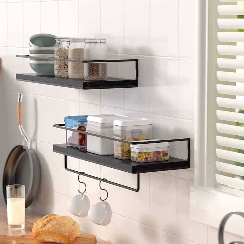 Wall-mounted kitchen shelves with storage jars, containers, and hanging mugs