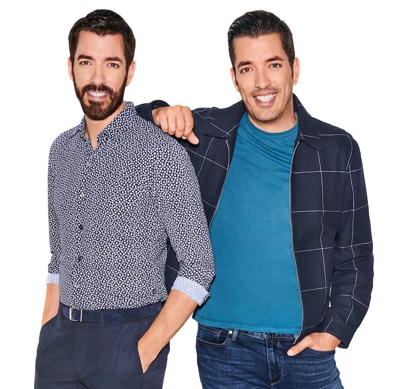 Drew and Jonathan Scott stand together with Jonathan resting his arm on Drew