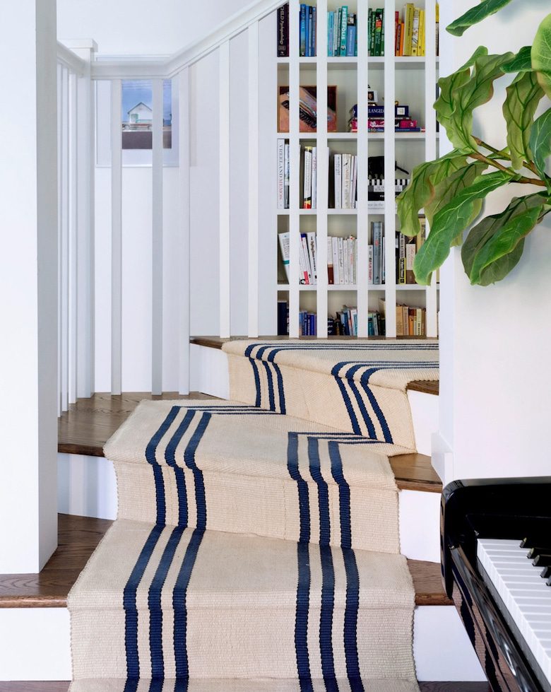Curved staircase with beige and navy striped carpet runner