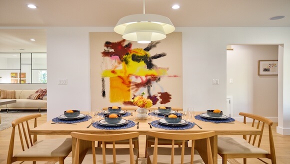 Dining room table set with large colorful painting on wall