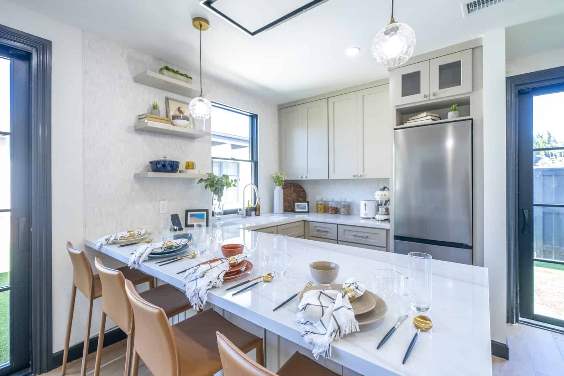 Modern kitchen with white marble island, leather barstools, open shelving, and stainless steel appliances