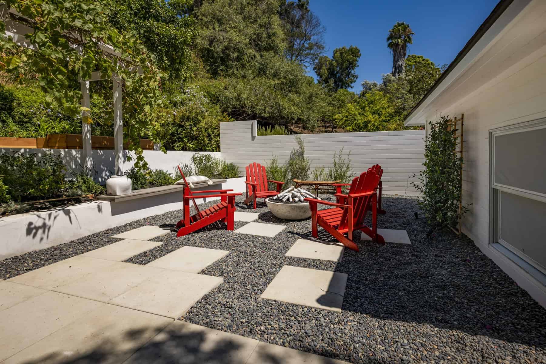 Outdoor fire pit area with red Adirondack chairs and modern landscaping