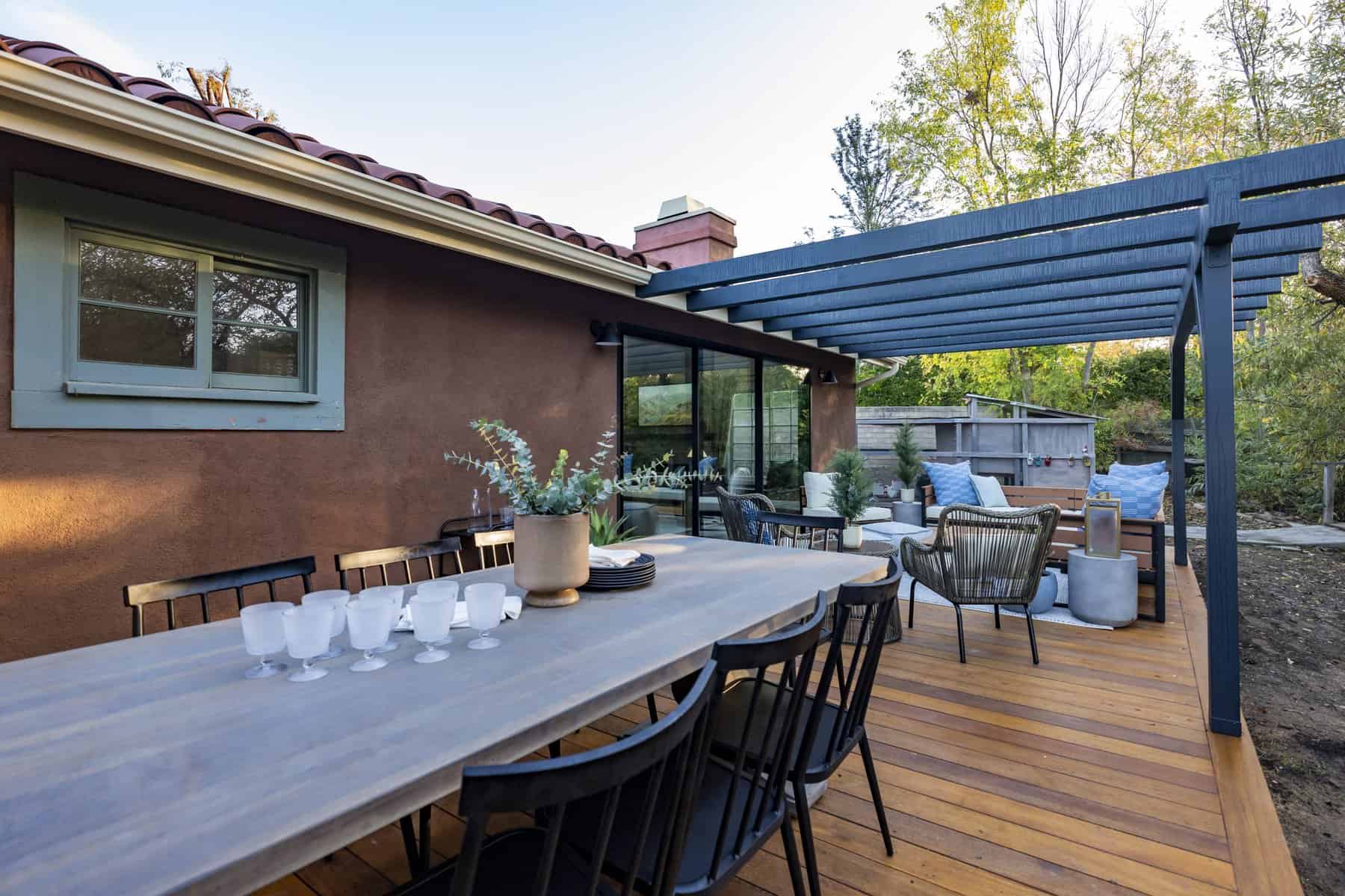 Outdoor dining table with black chairs under a blue pergola