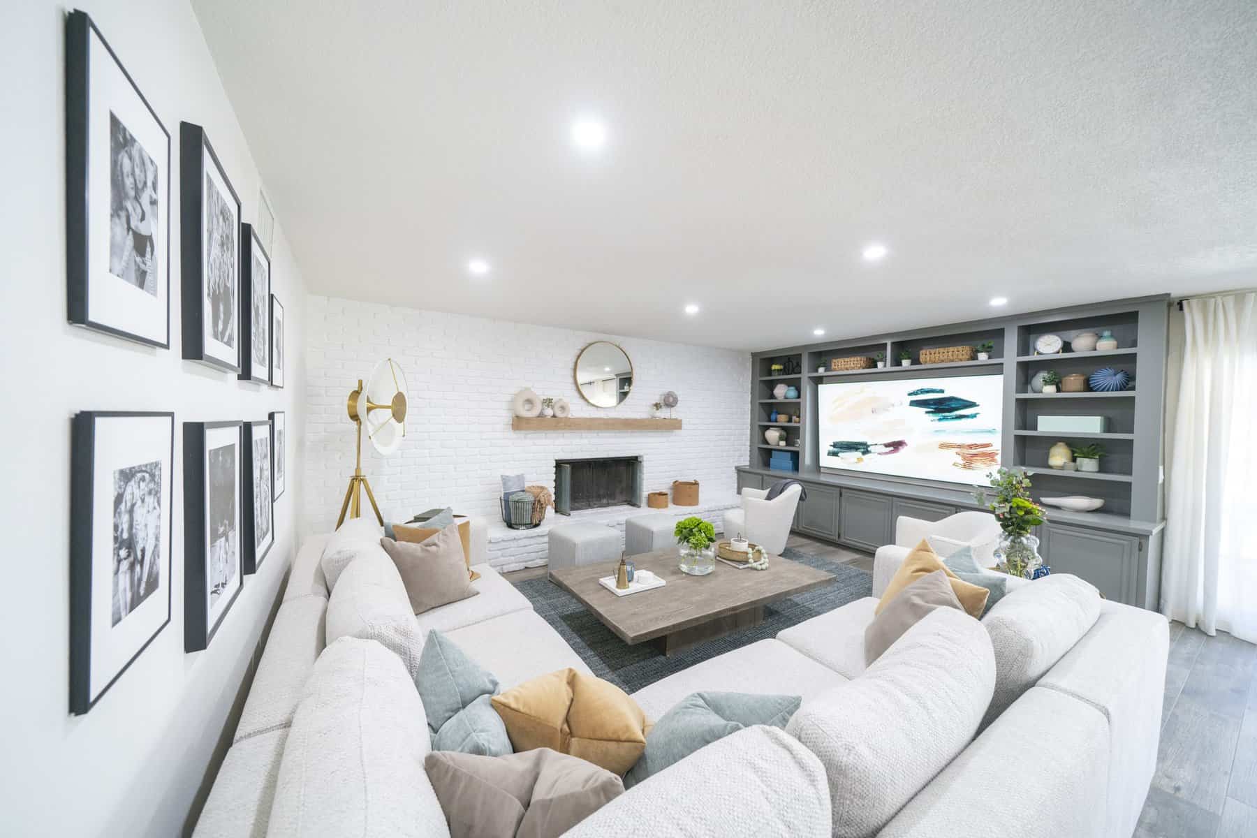 Bright living room with a white sectional sofa, built-in shelves, a fireplace, and framed wall art